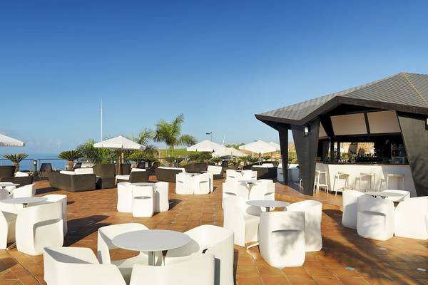 Außenbereich des H10 Playa Meloneras Palace Hotels mit weißen Stühlen und Tischen, Schirmen und Blick aufs Meer.