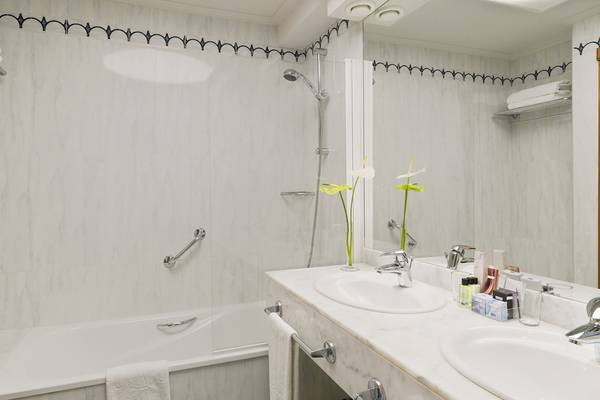 Badezimmer im H10 Playa Meloneras Palace mit Badewanne, Dusche, Waschbecken und Spiegeln.