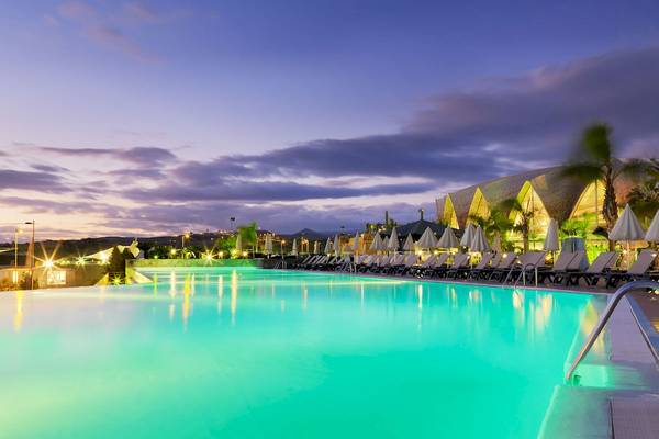 Pool mit Sonnenliegen und Palmen am Abend im H10 Playa Meloneras Palace Hotel