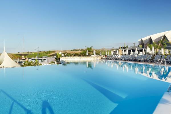 Außenpool des H10 Playa Meloneras Palace Hotels mit Sonnenliegen und Sonnenschirmen.