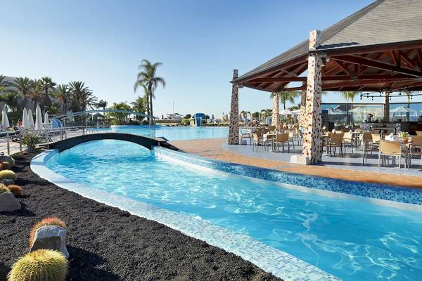 Außenpoolbereich des H10 Playa Meloneras Palace mit Brücke und Loungebereich.