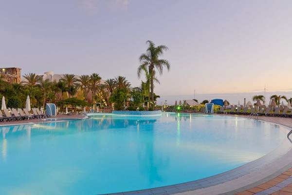 Außenpool des H10 Playa Meloneras Palace mit Palmen und Sonnenliegen