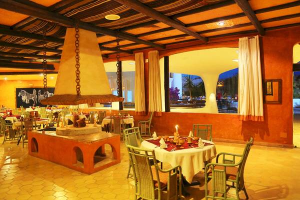 Innenansicht des Restaurants im Odyssee Resort Thalasso & Spa mit Tisch, Stühlen und offenem Kamin.