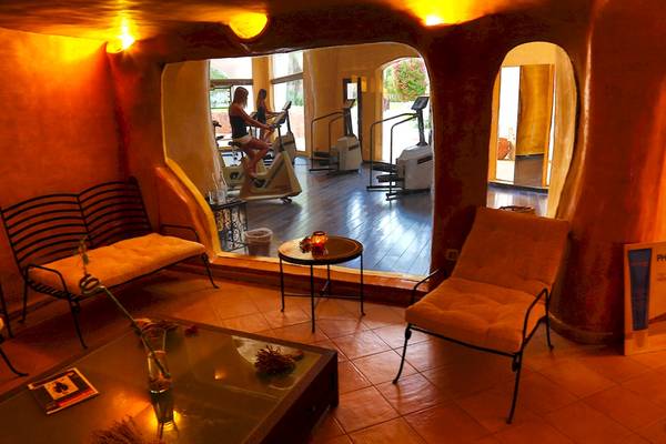 Fitnessraum im Odyssee Resort Thalasso & Spa mit einer Frau auf einem Fahrradtrainer und einer weiteren Person in der Ferne.