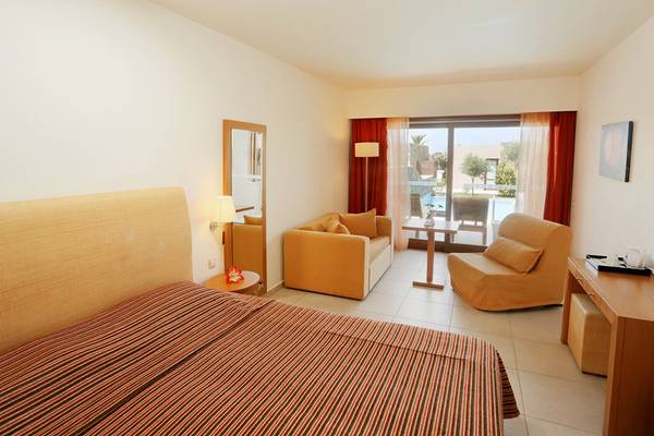 Hotelzimmer des Blue Sea Beach Affiliated by Melia mit Bett, Sitzbereich und Balkonzugang.