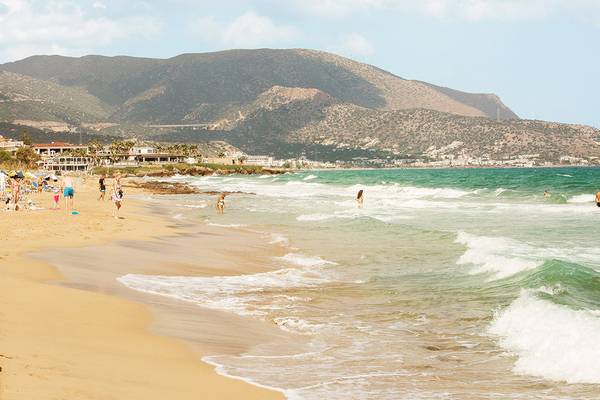 Strandlandschaft des Blue Sea Beach Affiliated by Melia mit Menschen und Bergen im Hintergrund.