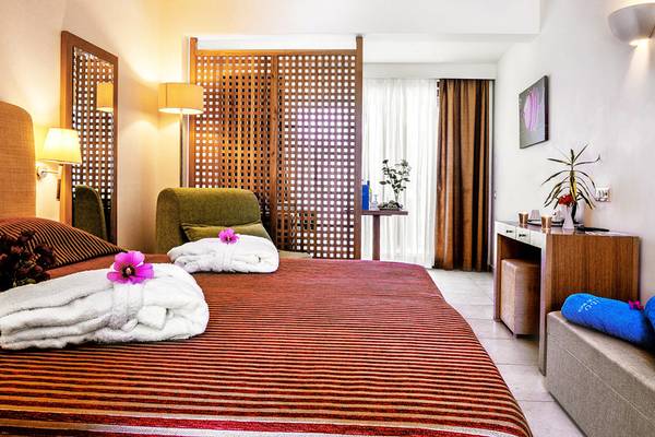 Hotelzimmer im Blue Sea Beach Affiliated by Melia mit Bett, Kissen, Lampen und Pflanzen.