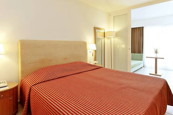 Zimmer im Blue Sea Beach Affiliated by Melia mit rotem Bett, Lampe und Nachttisch