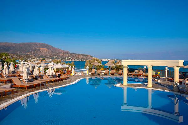 Außenpool des Alexander Beach Hotel mit Blick auf das Meer und eine Berglandschaft.