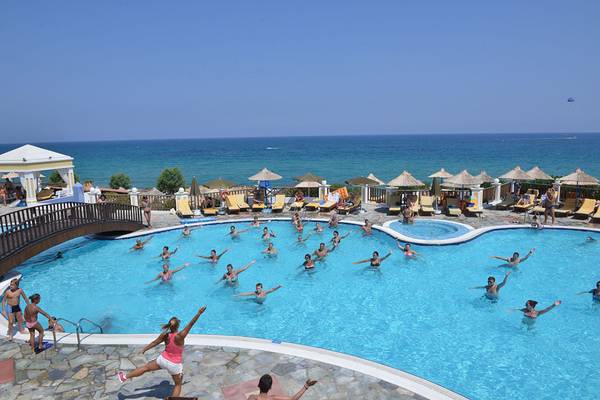 Alexander Beach Hotel & Village Resort Poolbereich mit vielen Schwimmern und Blick auf das Meer.