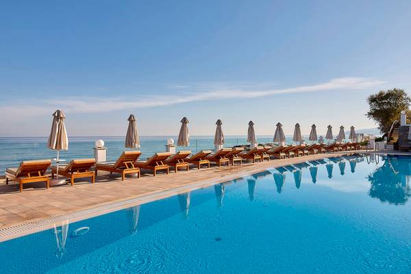Reihe von Liegestühlen am Pool des Alexander Beach Hotel mit Blick auf das Meer