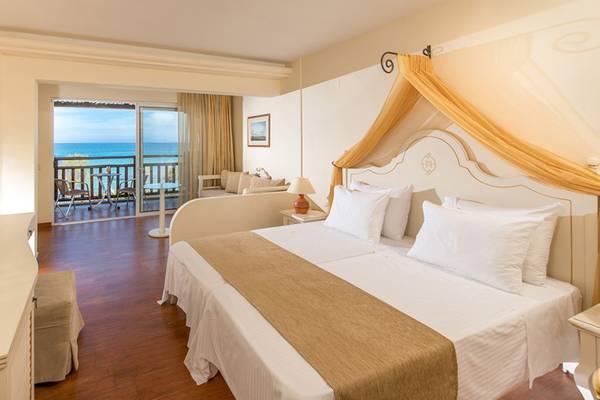 Zimmer im Alexander Beach Hotel mit Meerblick, Doppelbett, Balkon und offenem Wohnzimmer.