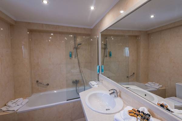 Badezimmer im Alexander Beach Hotel & Village Resort mit Badewanne, Waschbecken und Spiegel.
