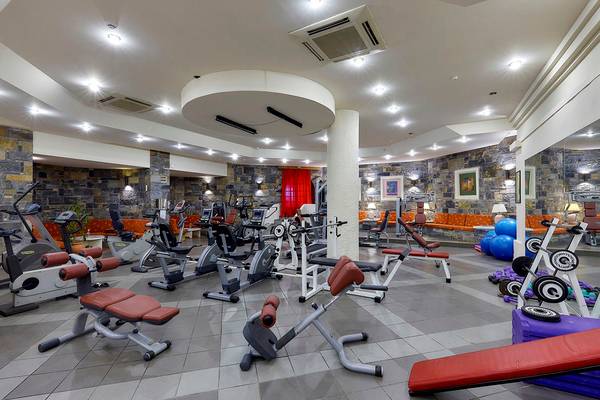 Fitnesscenter im Alexander Beach Hotel & Village Resort mit verschiedenen Trainingsgeräten und Steinwänden.