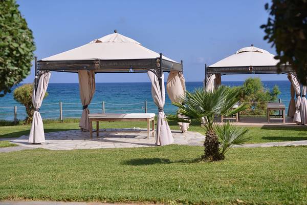 Zwei Gazebos am Strand des Alexander Beach Hotel & Village Resort mit Blick auf das Meer.