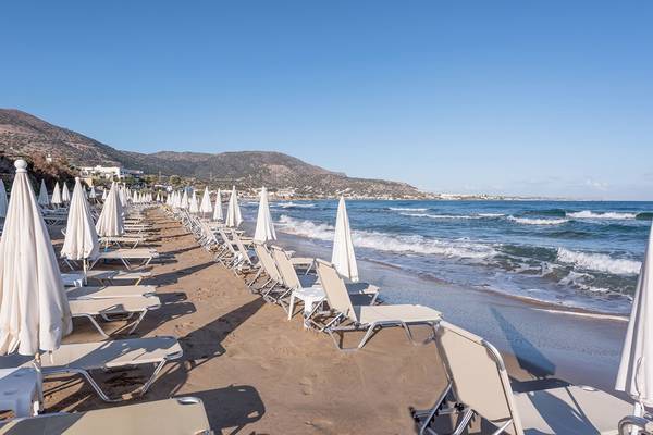 Alexander Beach Hotel Strand mit Sonnenliegen und Schirmen am Meer