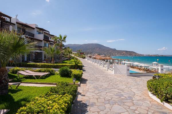 Weg zum Strand am Alexander Beach Hotel & Village Resort mit Blick auf Gebäude, Palmen und Meer.