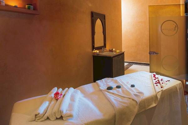 Massageraum im Hotel Pickalbatros Aqua Fun Club mit weißem Bett, Handtüchern, Rosenblättern und einem Spiegel.