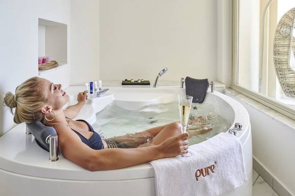 Frau im Whirlpool im Steigenberger Pure Lifestyle Hotel mit einem Glas Champagner.