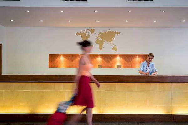 Eine Frau mit Koffern geht an der Rezeption des Bella Beach Hotels vorbei.