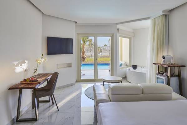 Ein modernes Hotelzimmer mit einem Schreibtisch, einer Couch und einem Blick auf den Pool.