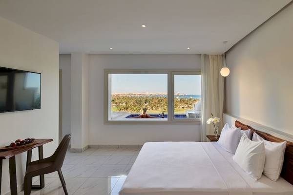 Zimmer im Steigenberger Pure Lifestyle mit Blick auf das Meer und eine Frau im Pool.