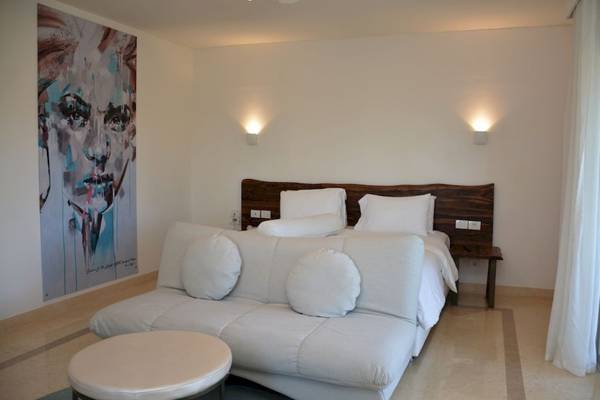 Ein modernes Schlafzimmer im Steigenberger Pure Lifestyle Hotel mit weißen Möbeln und einer großen Wandmalerei.