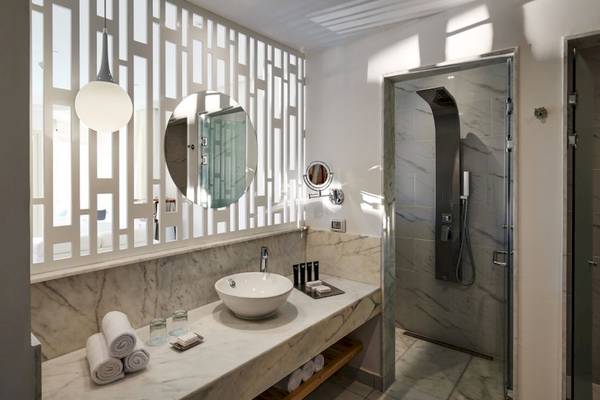 Badezimmer im Steigenberger Pure Lifestyle Hotel mit Marmordekoration, Spiegel und Regendusche.