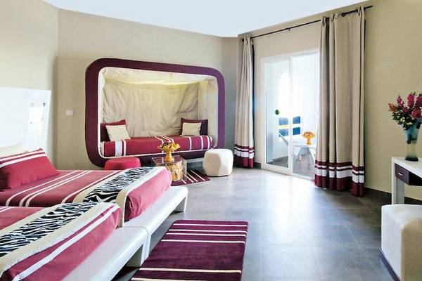 Schlafzimmer im Fiesta Beach Djerba Hotel mit zwei Betten, einem Baldachin und einer Glastür.