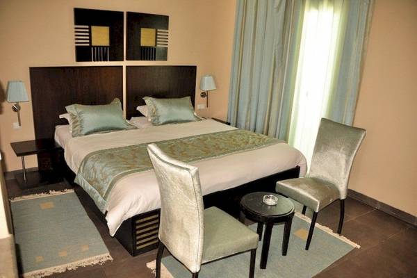 Doppelbett-Zimmer im Fiesta Beach Djerba Hotel mit modernen Möbeln und blauen Vorhängen.