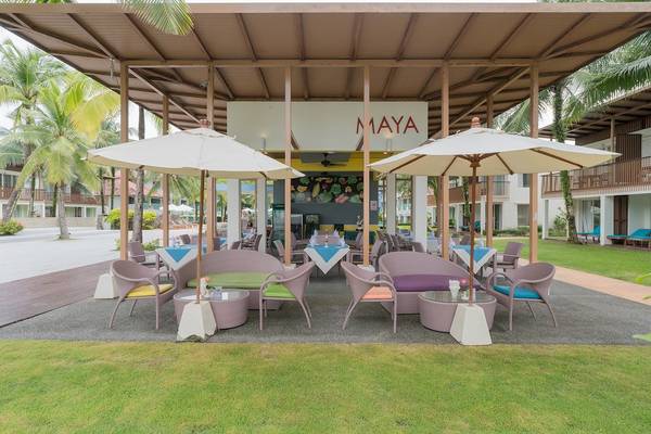 Außenterrasse des Maya Bereichs im Briza Beach Resort mit bunten Stühlen und Tischen.