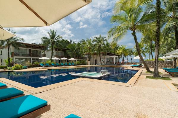 Pool-Loungebereich im Briza Beach Resort mit blauen Liegen und Sonnenschirmen.