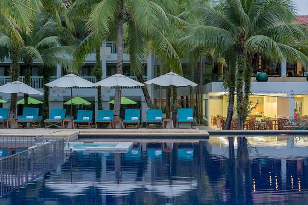 Pool-Loungebereich im Briza Beach Resort mit blauen Sonnenliegen und weißen Sonnenschirmen.
