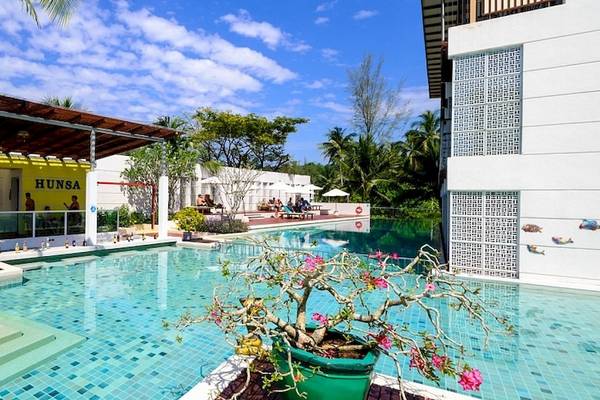 Der Poolbereich des Briza Beach Resorts mit gelbem Gebäude und Pflanzen.
