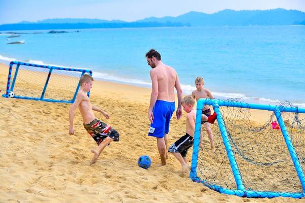 Vater und Kinder spielen Fußball am Strand des Briza Beach Resort