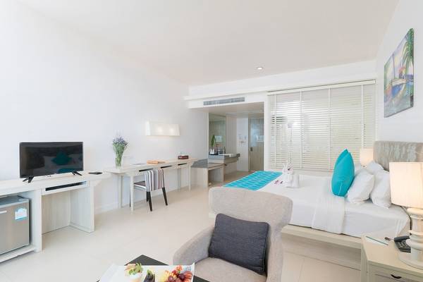 Das moderne Hotelzimmer im Briza Beach Resort mit Fernseher, Schreibtisch, Sessel, Bett und Obstplatte.