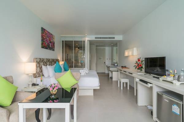 Hotelzimmer im Briza Beach Resort mit Bett, Sofa, Tisch, Fernseher und Blumen.