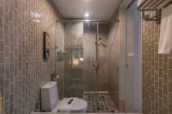 Dusche im Briza Beach Resort mit Fliesenwänden, Glasdusche und Toilette.