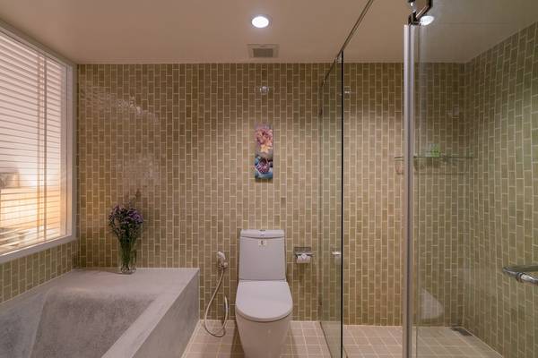 Badezimmer im Briza Beach Resort mit grünen Kacheln, Badewanne, Toilette und Glasdusche.