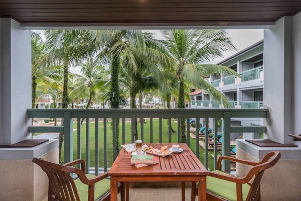 Balkon des Briza Beach Resorts mit Tisch, Getränken und Büchern auf einem Rasen.