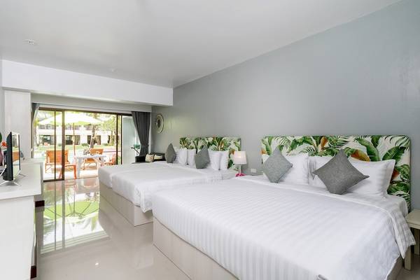 Zwei geräumige Schlafzimmer im Briza Beach Resort mit weißen Betten und grünen Kopfteilen.