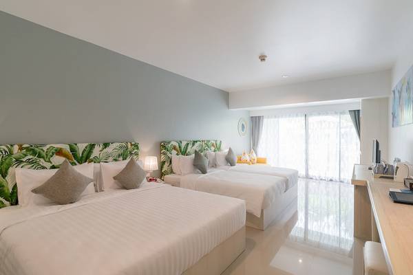 Hotelzimmer im Briza Beach Resort mit drei Betten, weißem Dekor und grünen Kopfteilen.