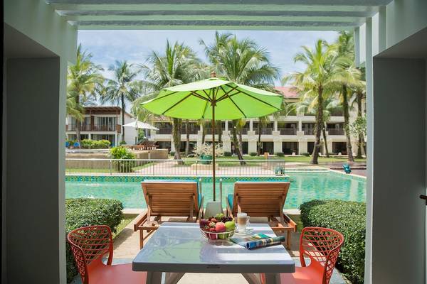 Außensitzecke des Briza Beach Resorts mit grünem Sonnenschirm und Pool im Hintergrund