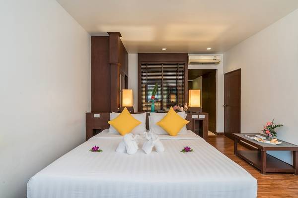 Zweibettzimmer im Briza Beach Resort mit weißen Laken, gelben Kissen und Blumendekoration.