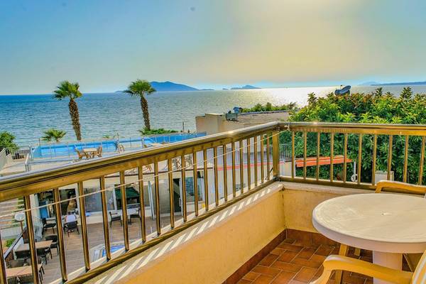 Balkon mit Meerblick im Malhun Hotel, inklusive Tisch, Stühlen, Palmen und Swimmingpool.