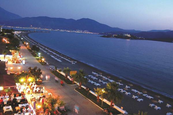 Abendlicher Blick auf den Strand des Malhun Hotels mit vielen Liegen und Palmen.