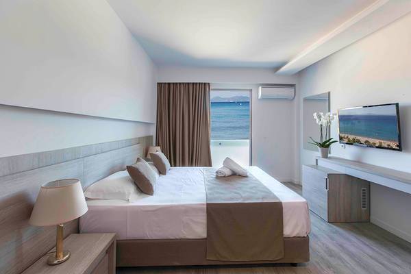 Schlafzimmer im Akti Imperial Deluxe Resort mit Meerblick, Flachbildfernseher und Fenstern.