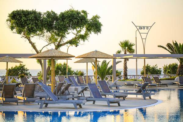 Sonnenuntergang am Poolbereich des Akti Imperial Deluxe Resort & Spa mit Liegen und Schirmen.