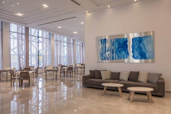 Loungebereich eines Hotels mit einem Sofa, zwei kleinen Tischen und einer großen Wandkunst.