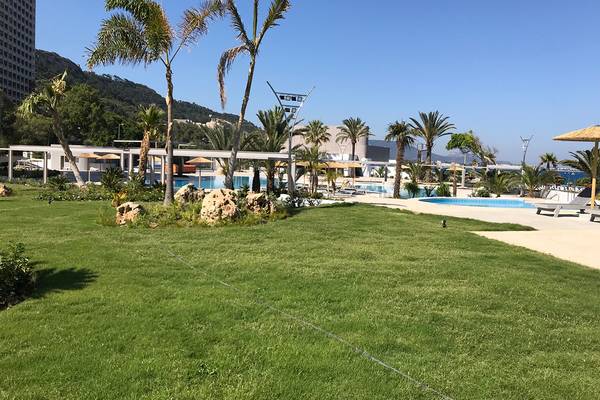 Poolbereich des Akti Imperial Deluxe Resorts mit Palmen und Liegestühlen.